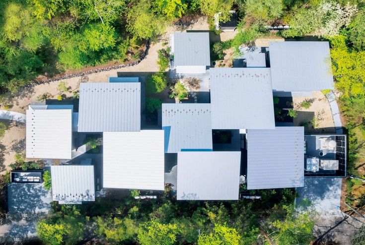 an aerial view of a house surrounded by trees in the middle of a forest area