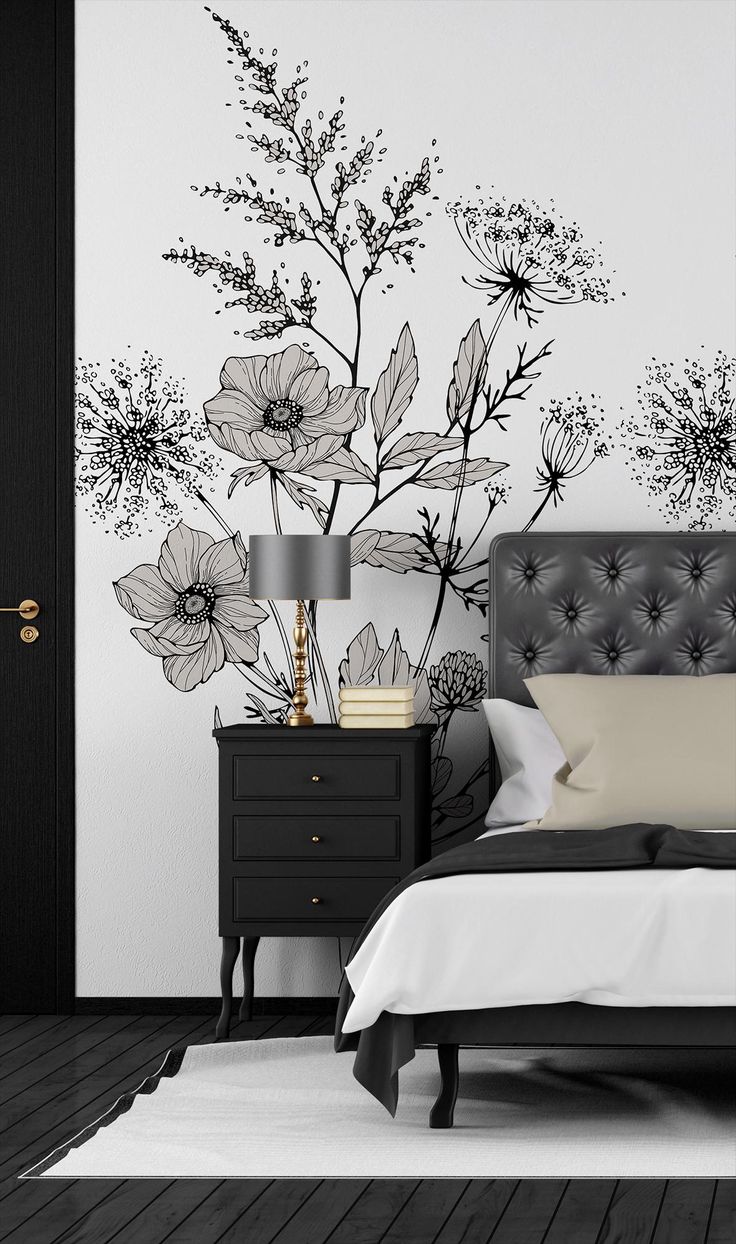 a black and white bedroom with flowers painted on the wall