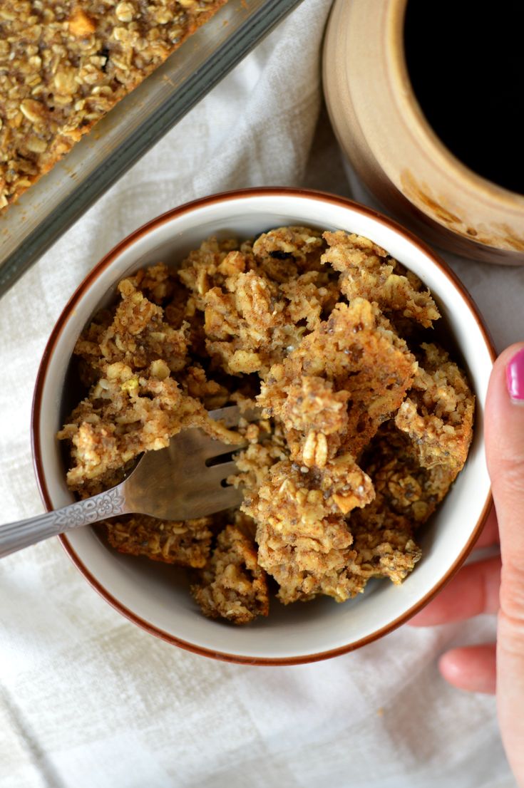 a hand holding a spoon over a bowl of granola