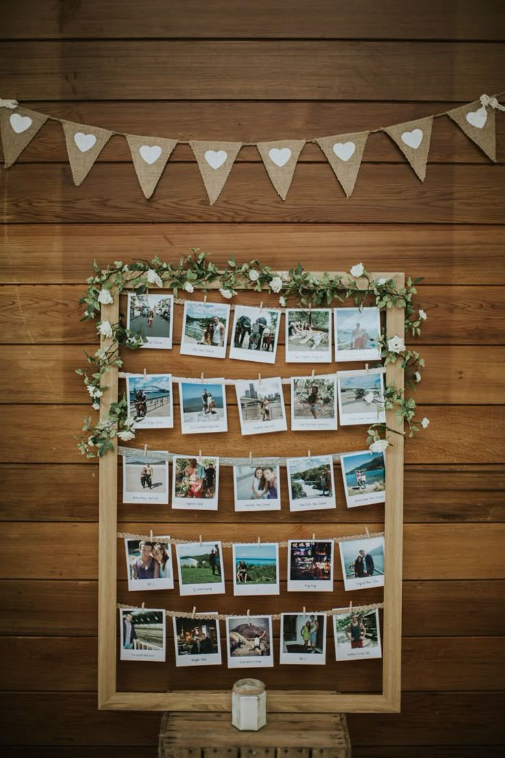 an old photo frame with photos hanging on it and garlands around the edges is decorated with greenery