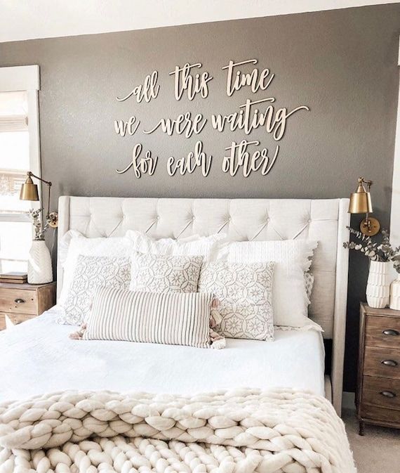 a white bed sitting under a metal wall sign