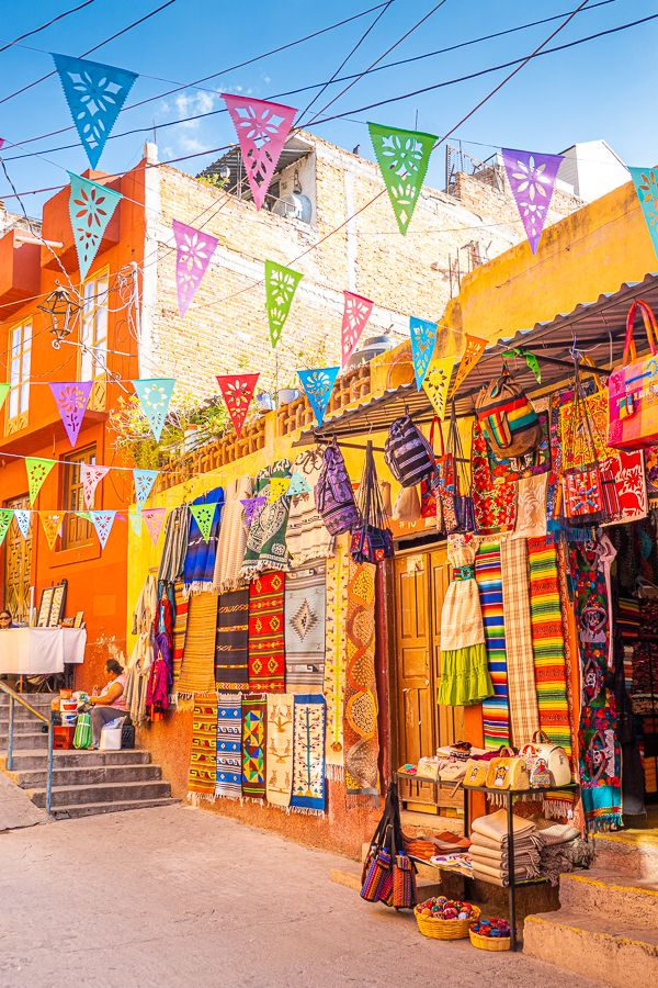 an outdoor market with lots of colorful items hanging from it's walls and windows