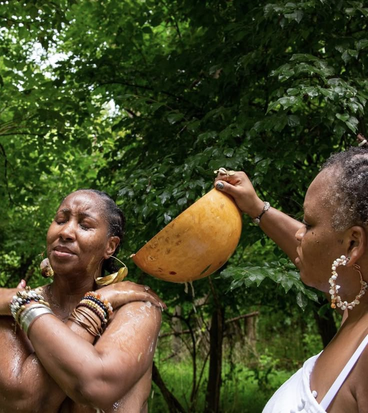 two women standing in the woods, one holding a large banana