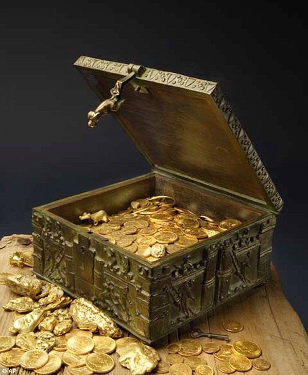 a wooden box filled with gold coins on top of a table