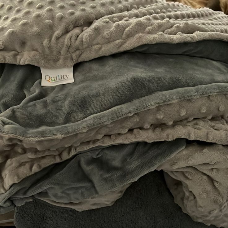 several blankets stacked on top of each other with a tag attached to the middle one