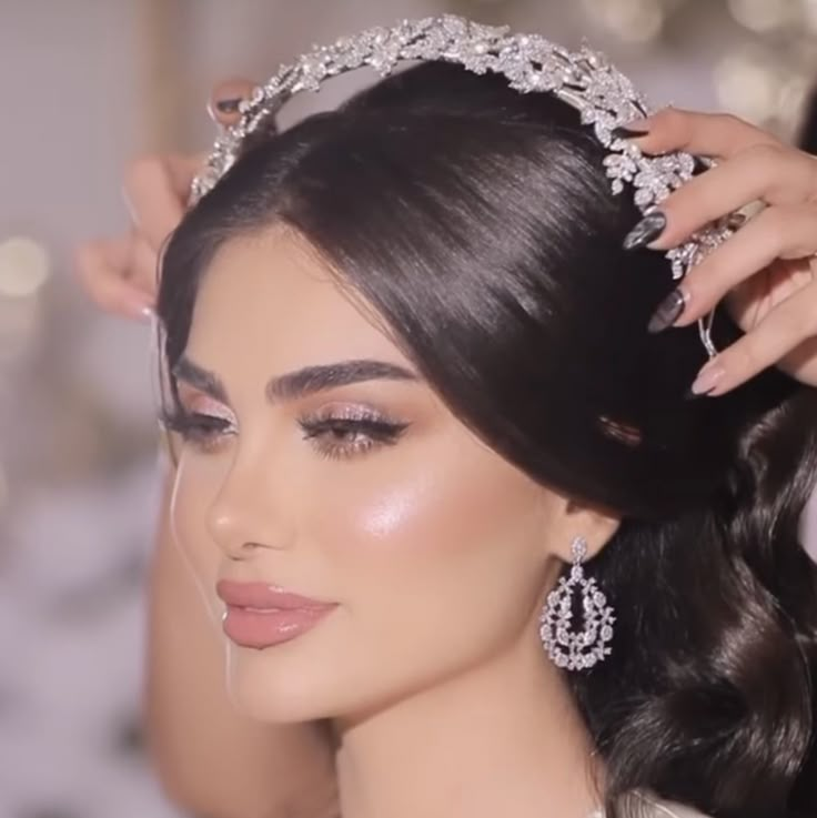 a woman is getting her hair done in a bridal gown and diamond tiara