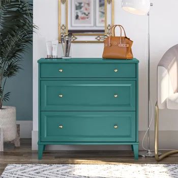 a blue dresser in a white room with a gold framed mirror on the wall above it