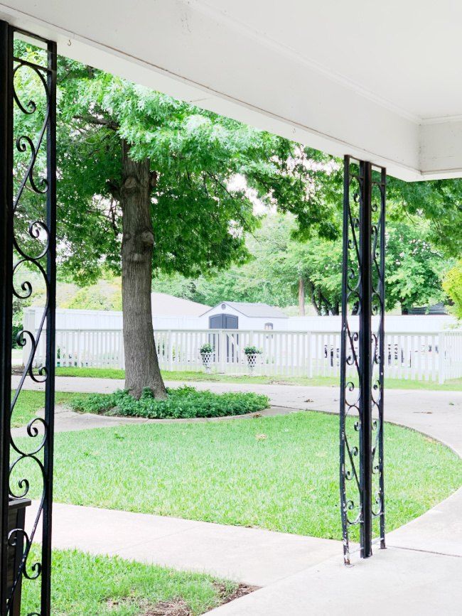 an open door leading to a yard with a tree in the middle and a white fence around it