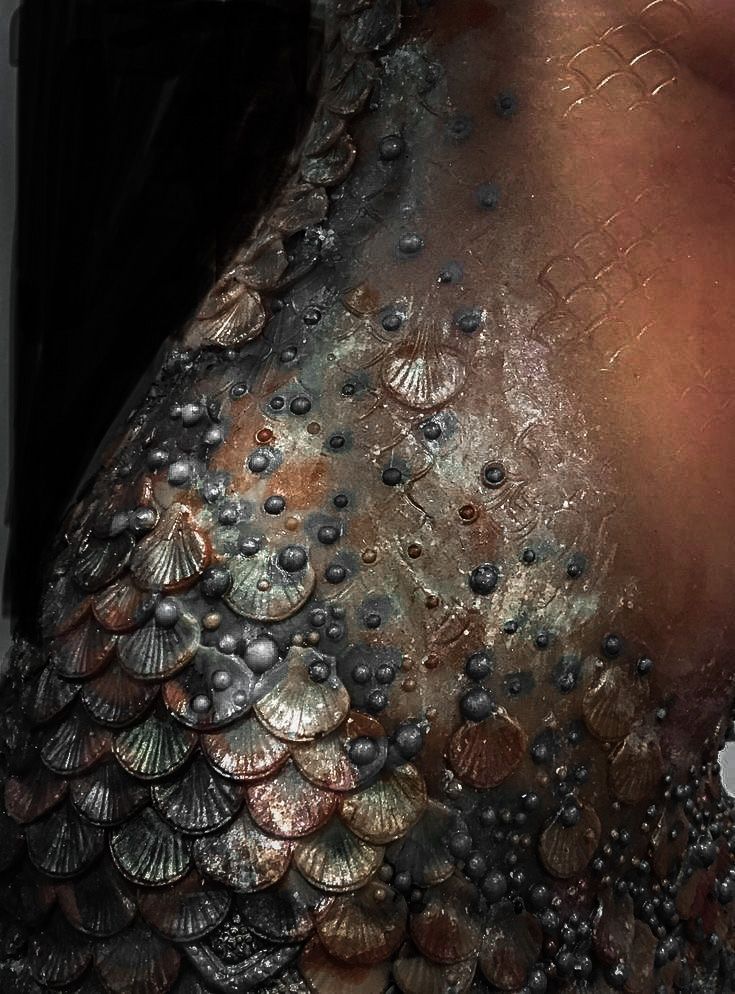 the back of a woman's body covered in water droplets and seashells