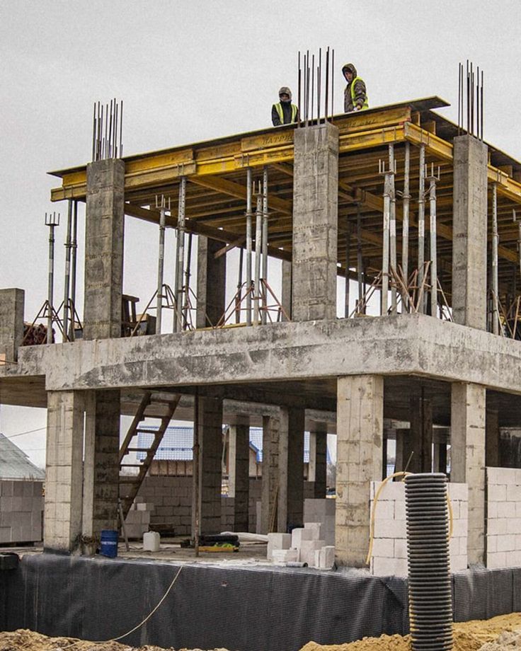 two men are standing on the roof of a building that is under construction with scaffolding