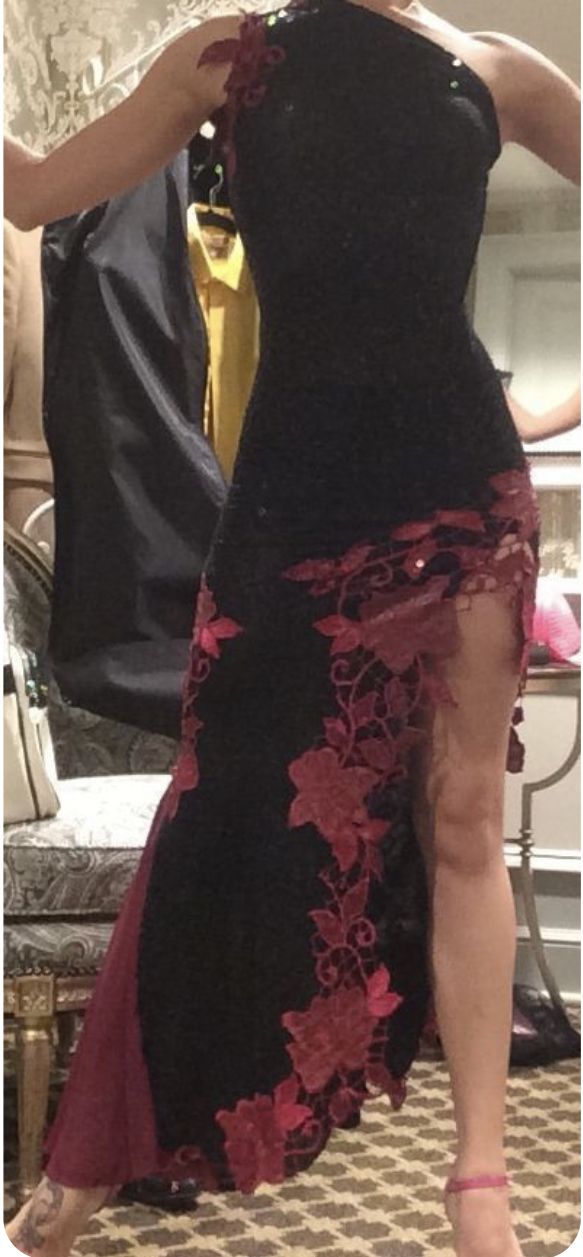 a woman in a black and red dress is standing near a mirror with her hand on her hip