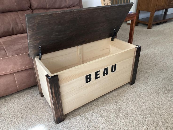 a wooden box with the word beau written on it sitting in front of a couch