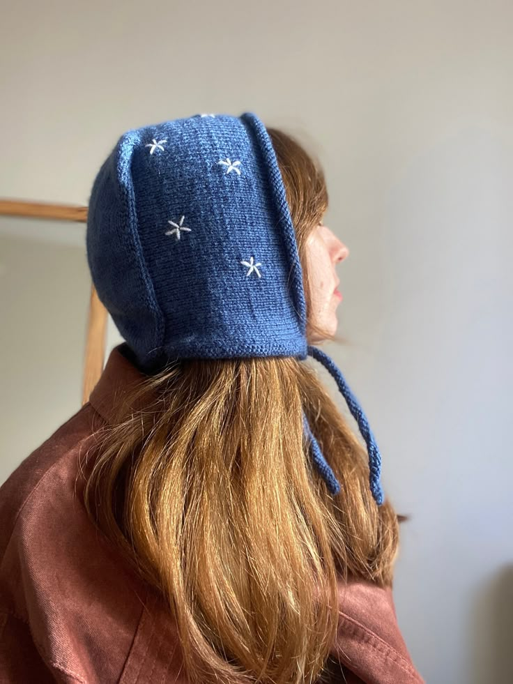 a woman wearing a blue hat with stars on it's brim is looking into the distance