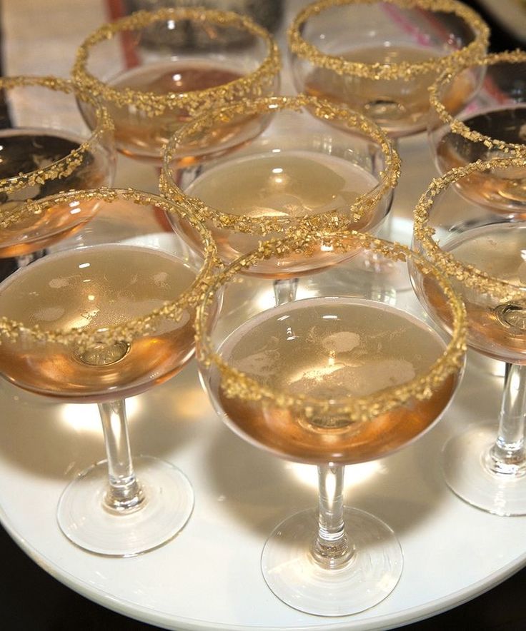 several glasses filled with different types of drinks on a white plate and black table cloth