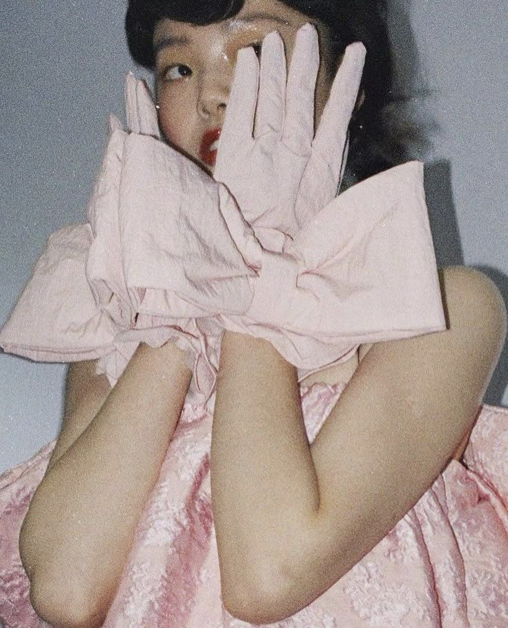 a woman in pink dress holding her hands up to her face