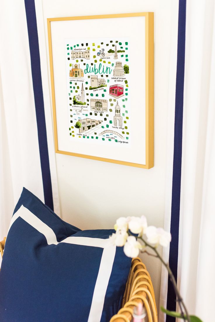 a blue and white pillow sitting on top of a wooden chair next to a painting