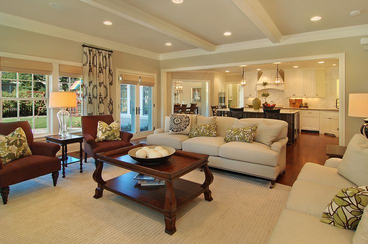 a living room with couches, chairs and tables in front of a kitchen area