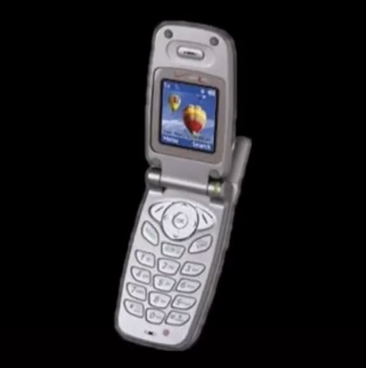 an old cell phone is shown in the dark with its screen turned on and open