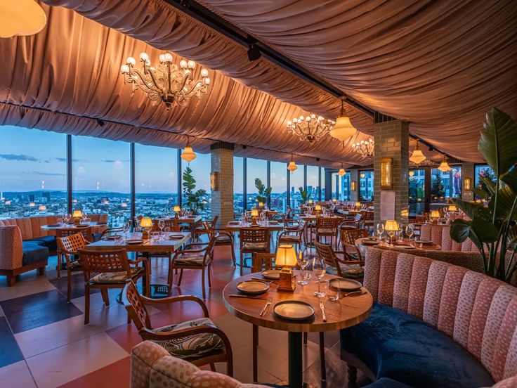 a restaurant with many tables and chairs in front of a large window overlooking the city