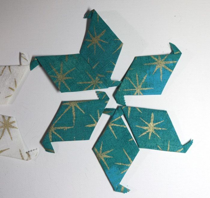 three pieces of paper with gold stars on them sitting next to each other in the shape of an origami snowflake