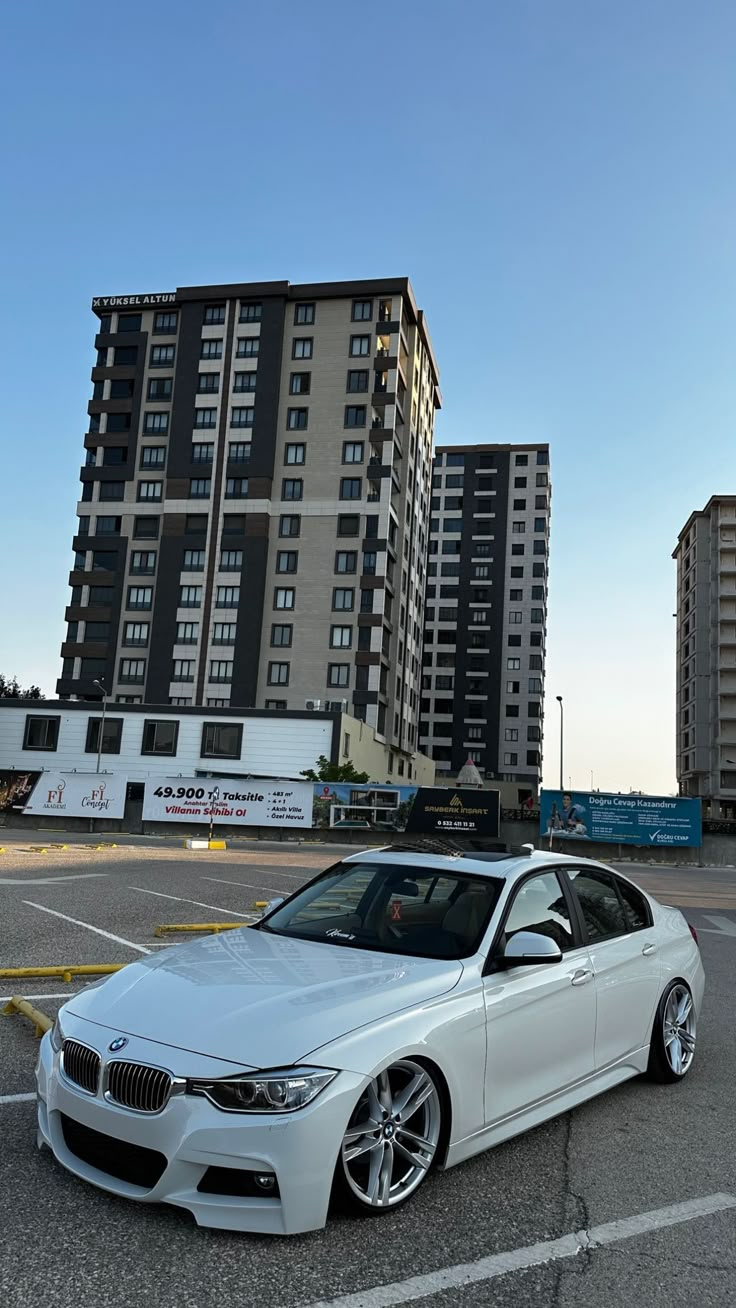 a white car parked in a parking lot next to tall buildings