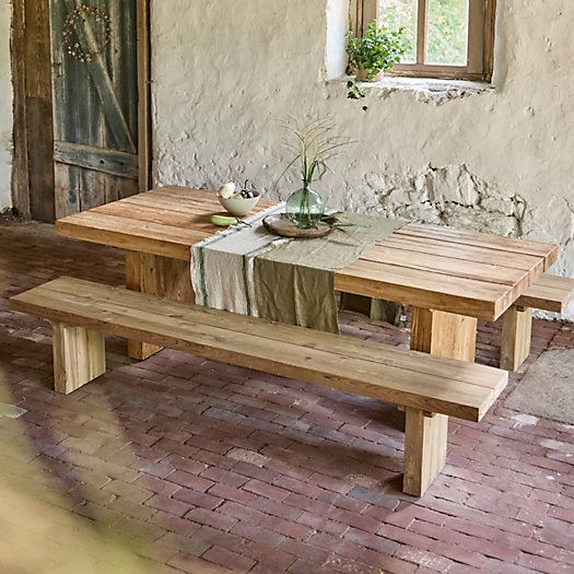 a wooden table sitting in front of a window on top of a red brick floor