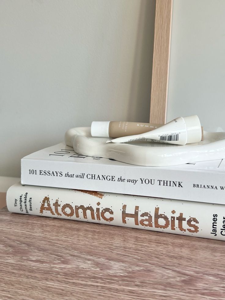 two books stacked on top of each other next to a light bulb and a mirror