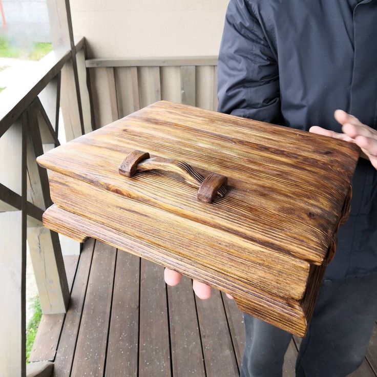 a man holding up a wooden box on a porch