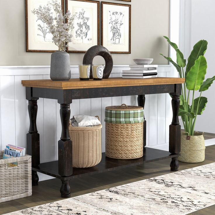 a wooden table with baskets on it in front of two pictures and a potted plant