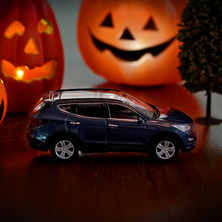 a toy car is parked in front of two carved jack - o'- lanterns