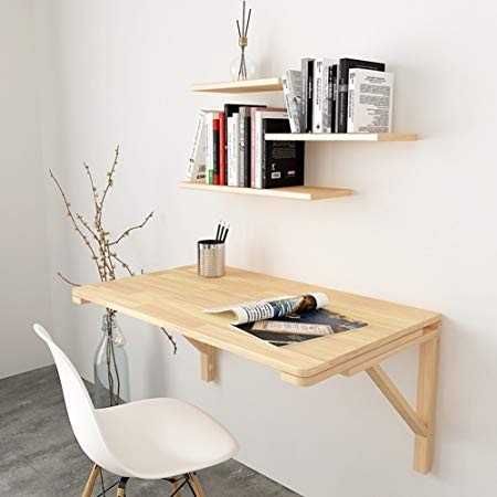 a wooden desk with books on it next to a white chair and wall mounted shelves