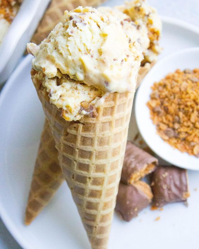 two cones of ice cream on a plate with other desserts in bowls behind them