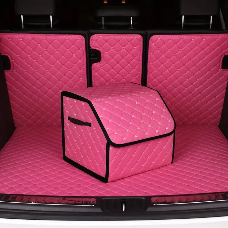 the trunk area of a car with two pink bags on it's back end