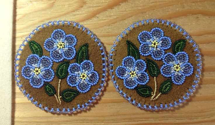 two small blue flowers are sitting on a wooden surface