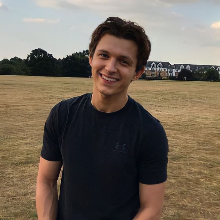 a young man is standing in the middle of an open field with houses in the background