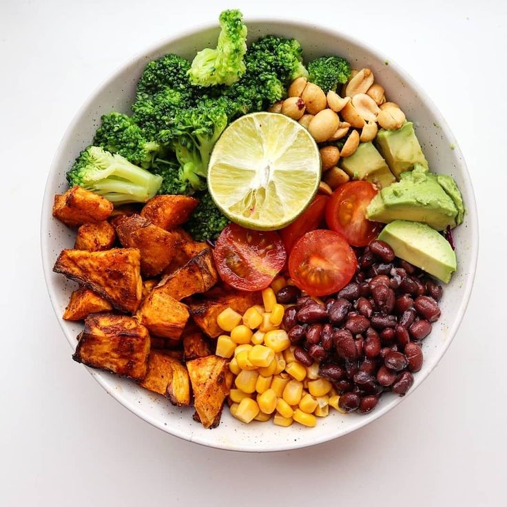 a white bowl filled with different types of vegetables and fruits on top of each other