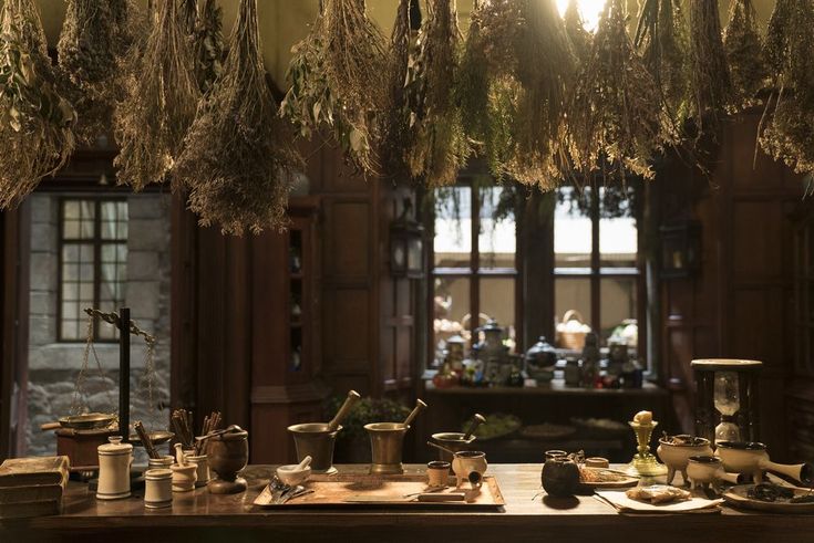 an old fashioned kitchen with many pots and pans hanging from the ceiling