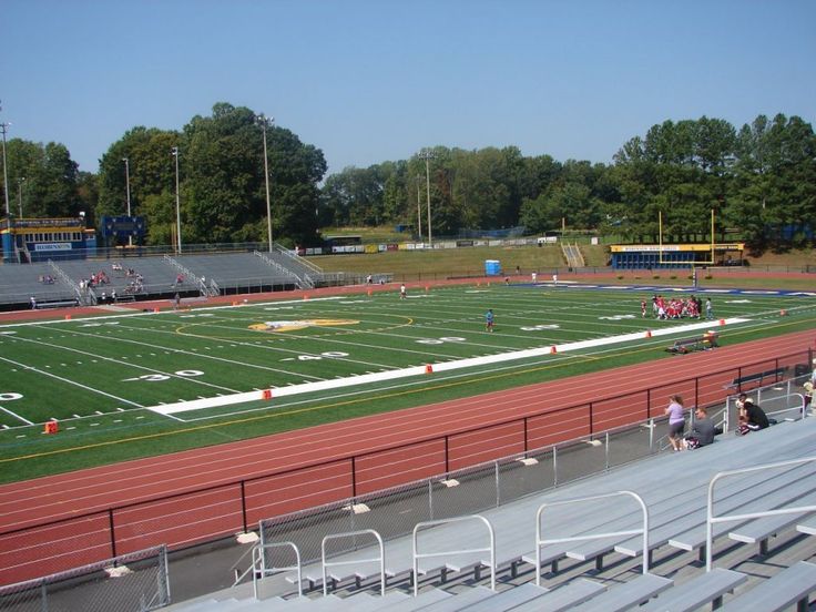 an empty football field with people sitting on the bleachers