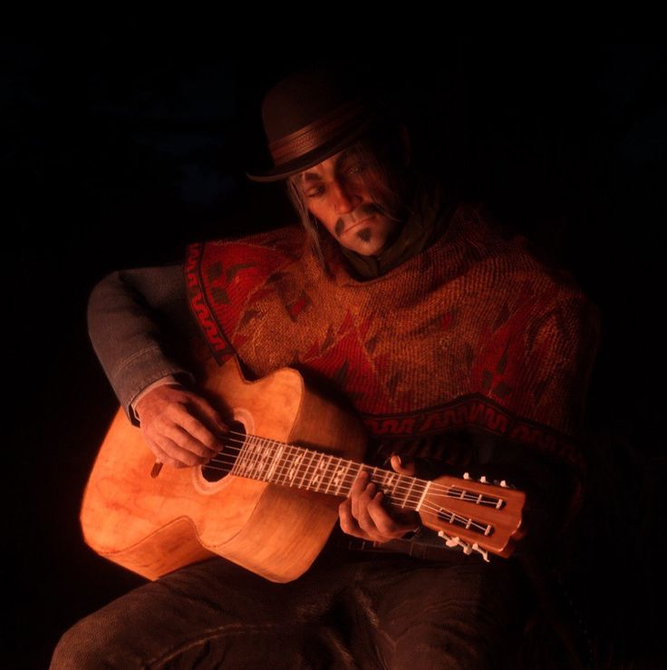 a man sitting in the dark playing an acoustic guitar