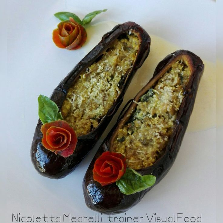 two stuffed eggplant halves with flowers and leaves on the top one is decorated with crumbs