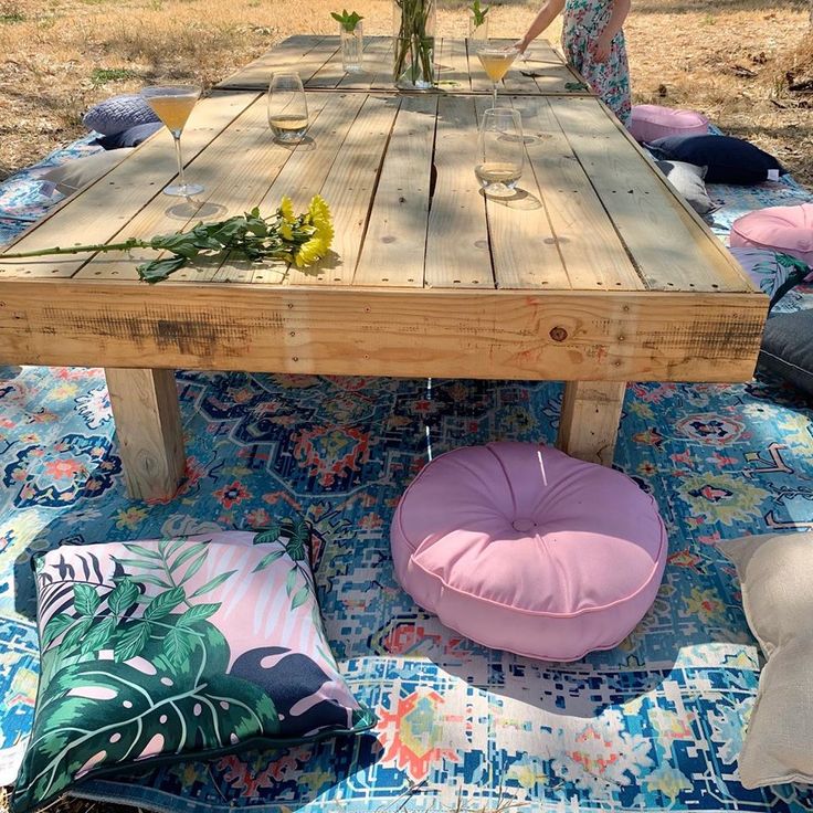 a table made out of pallet wood with flowers on top and pillows around it