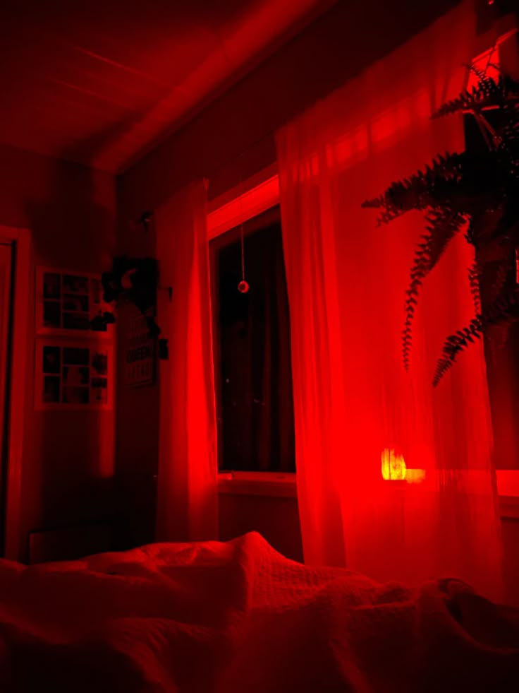 a bedroom with red light coming from the window