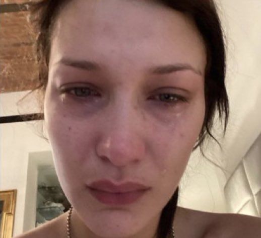 a close up of a person wearing a necklace and looking at the camera with tears on her face