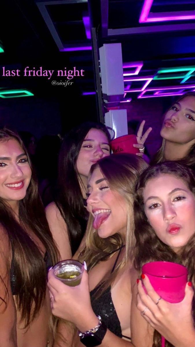 a group of young women standing next to each other at a nightclub with drinks in their hands