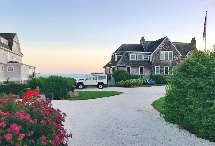 a white truck is parked in front of a house with flowers on the side walk