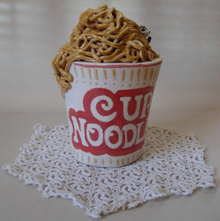 a cup with noodles in it sitting on a doily