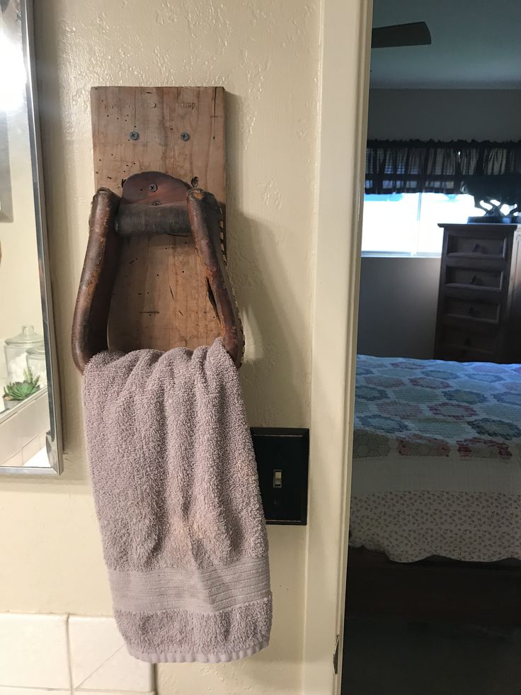 an old wooden towel rack hanging on the wall next to a bed in a bedroom