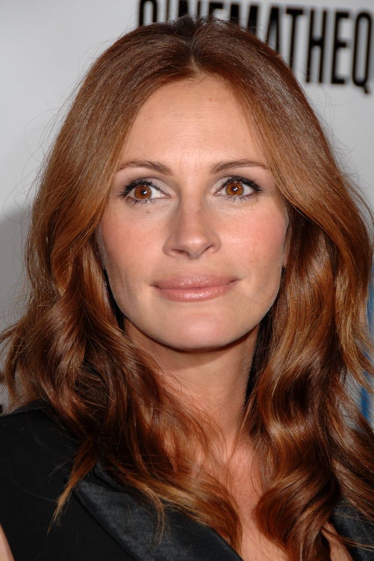 a woman with long red hair posing for the camera