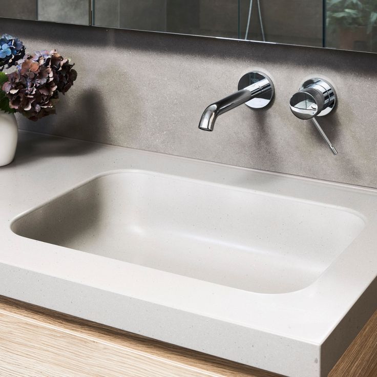 a bathroom sink with two faucets and a vase on the counter next to it