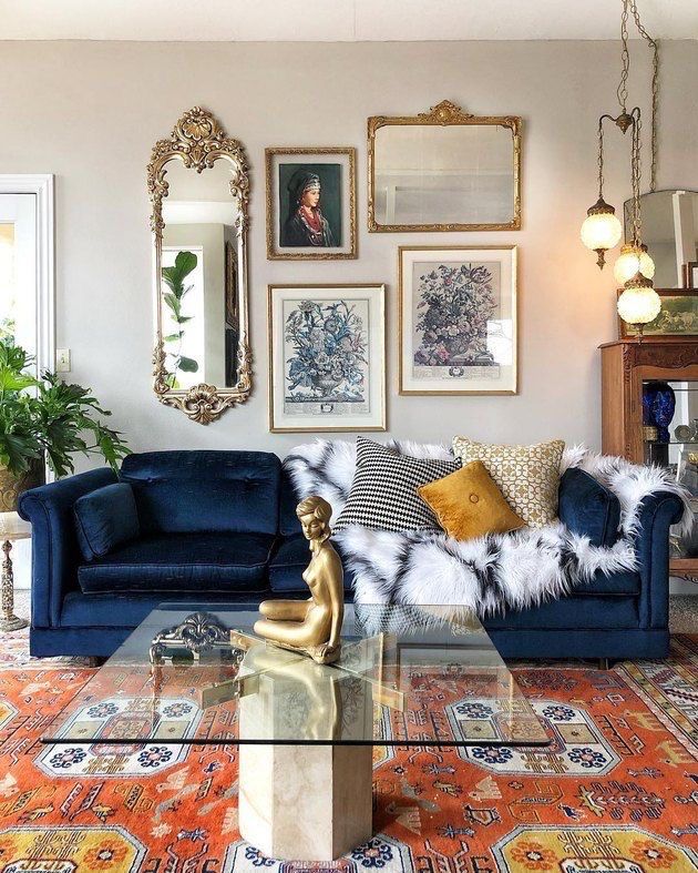 a living room with blue couches and pictures on the wall above them, along with a glass coffee table